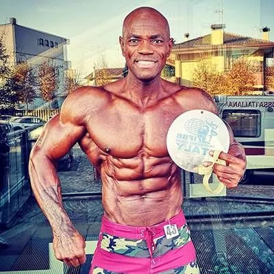 Antony Bessala holding a round IFBB Italy medal outdoors