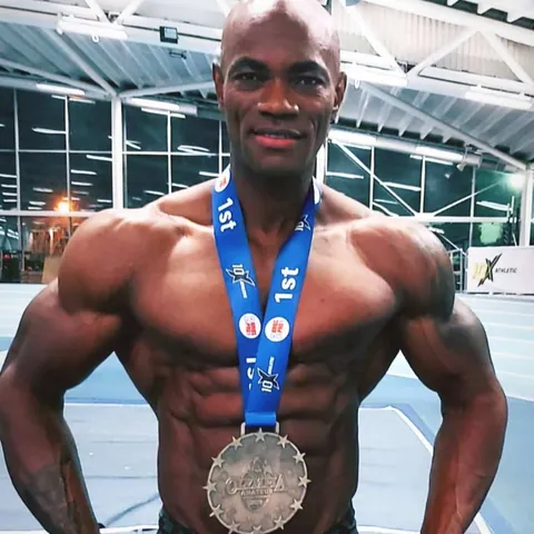 Close-up of Antony Bessala smiling with a 1st place Olympia-style medal